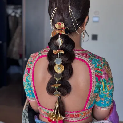 A beautiful example of an embellished bubble braid. This traditional hairstyle is elevated with intricate gold and pearl accessories, making it perfect for a bride.