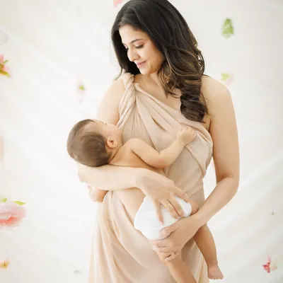 A mother's gentle gaze at her newborn. This portrait, with its soft light and ethereal floral background, feels like a painting of the purest love.