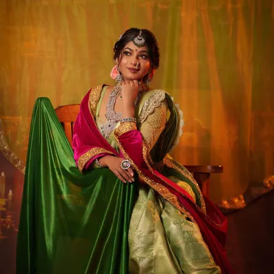 A full-length portrait of the 'Peshwe Bai' or Maratha queen look. Seated with poise, this image showcases the complete royal attire, including the unique draping style and rich fabrics.