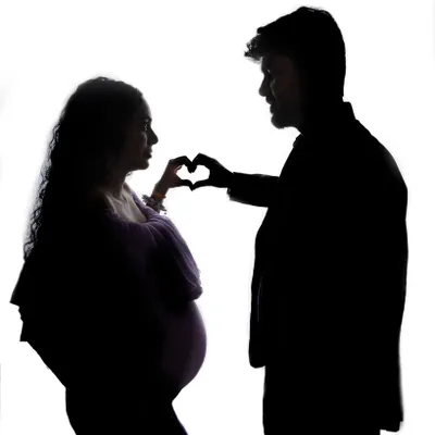 A beautiful silhouette of a couple creating a heart with their hands. This artistic shot is a simple yet powerful symbol of their love.