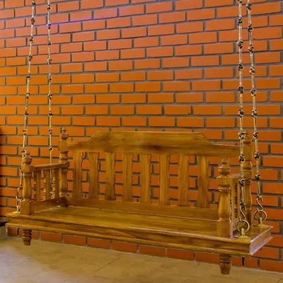 The traditional wooden 'jula', or swing, is a centerpiece in this home, set against a warm exposed brick wall. It’s a nostalgic element that invites relaxation and conversation.