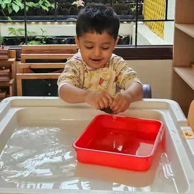 The simple joy of splashing in water. This child is exploring the properties of water while having fun, a core component of our sensory play philosophy.