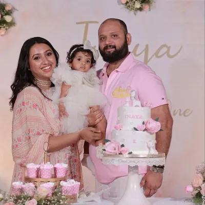 A beautiful family portrait at their daughter's first birthday. The soft pink and floral decor creates a gentle and loving atmosphere for the celebration.