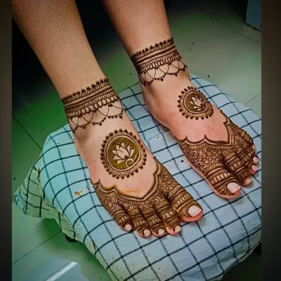 A simple and elegant foot mehandi design featuring a lotus mandala on the center of the foot and a delicate chain-like pattern around the ankle.