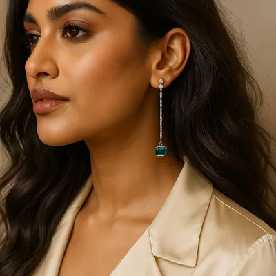 Crafted for the woman who defines her own elegance. These long drop earrings feature a stunning square-cut green stone, suspended from a chain of sparkling diamonds. They are designed to speak without saying a word.