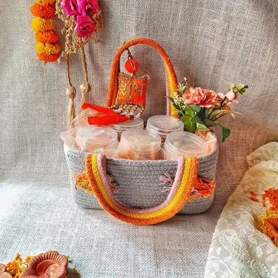 This Diwali hamper is designed with a traditional touch. It comes in a lovely woven basket and includes jars of treats, decorated with marigold flowers and a "Shubh Labh" charm to share festive blessings.