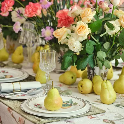 In the dining room of 'The Blooming Garden', a heritage renovation, we created a tablescape that feels both abundant and intimate. The mix of fresh pears, floral arrangements, and printed linens complements the room's blush-toned floral wallpaper and refurbished furniture.
