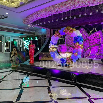 This photo shows the scale of a grand 'Welcome Baby' stage I designed for a banquet hall. The circular balloon arch and neon sign create an impressive centerpiece for the event.