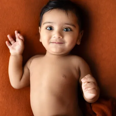 Six months old and full of personality. This little one's curious eyes and sweet smirk are a perfect example of the adorable expressions we capture during sitter sessions.