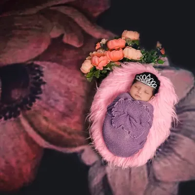 A little princess is born. This newborn is wrapped in a beautiful floral theme, complete with a tiny tiara, showcasing our creative approach to newborn photography.
