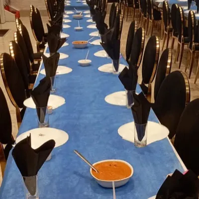 A long view of our formal dining setup. The striking blue and black theme, with neatly folded napkins and pre-set dishes, shows our ability to execute a sophisticated and large-scale seated dinner service.