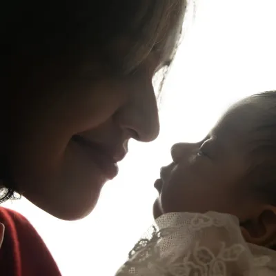 A powerful silhouette shot capturing the tender profile of a mother as she looks down at her newborn baby, highlighting their instant, profound connection.