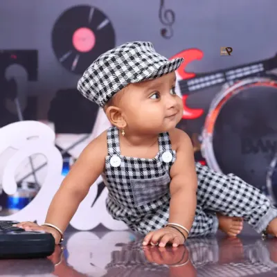A little rockstar in the making! This baby in a checkered outfit and cap looks cool and confident in a music-themed setup, complete with guitars and records.