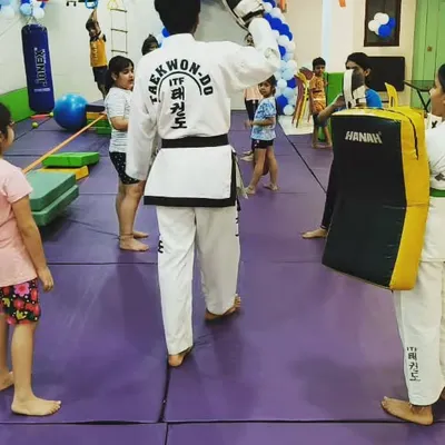 A Taekwondo player doesn't need a weapon, they are one. Here, an instructor guides a student through punching drills, focusing on technique and power in our safe, padded training area.