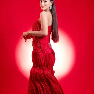 A high-fashion editorial shot featuring a model in a unique, textured red gown. The dramatic lighting and bold colour create a visually arresting image that is perfect for showcasing avant-garde or high-fashion makeup skills.