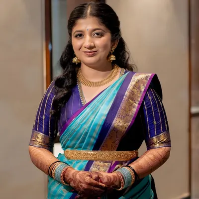 A full portrait of a client looking radiant in her silk saree. The mehendi on her hands and forearms adds a traditional and celebratory element to her elegant look.
