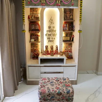 A beautiful and serene pooja unit. The arched niche with backlighting creates a divine glow. The unit has drawers for storage and is decorated with traditional marigold garlands.