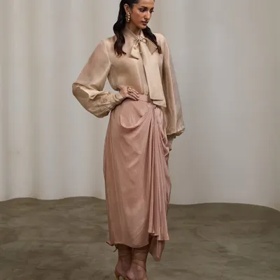 A full-length studio shot for a designer's pret couture line. The elegant pose and soft lighting highlight the graceful drape and flow of this indo-western outfit.