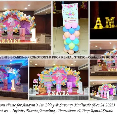 A magical unicorn theme for Amayra's first birthday. The setup features a circular backdrop with a unicorn illustration, a pastel rainbow balloon arch, and themed pedestals for a dreamy party.