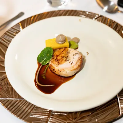A signature dish, the Ballotine of Chicken. This heritage chicken is deboned, stuffed with a mushroom mousseline, and served with panisse and a port wine reduction.