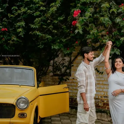 A playful shot of a couple dancing next to a bright yellow vintage car, adding a fun, retro vibe to their maternity photoshoot.