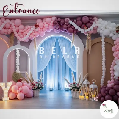 This grand entrance uses a multi-layered arch design with extensive balloon work in shades of pink and burgundy. The neon-lit central arch and draped fabric create a dramatic and welcoming entryway for an elegant celebration.