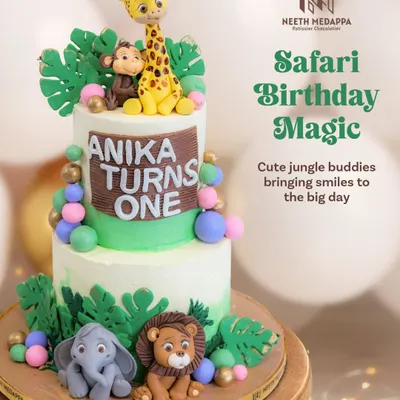 A full view of the two-tiered safari cake for Anika's first birthday, complete with a giraffe, monkey, lion, and elephant.