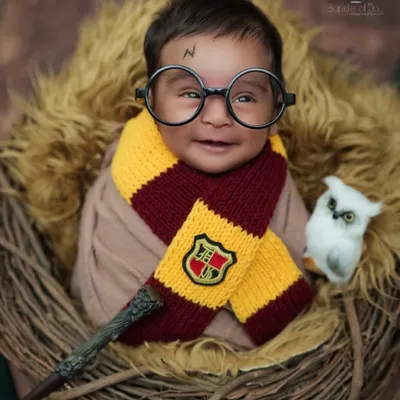 My most requested magical theme. This smiling baby is styled as Harry Potter, complete with the iconic glasses, scar, and a Gryffindor scarf, nestled in a nest with his wand.