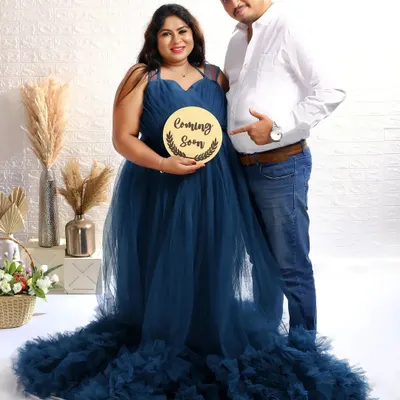A classic announcement shot with a "Coming Soon" sign. The dad-to-be playfully points to the baby bump, sharing their happy news with the world.