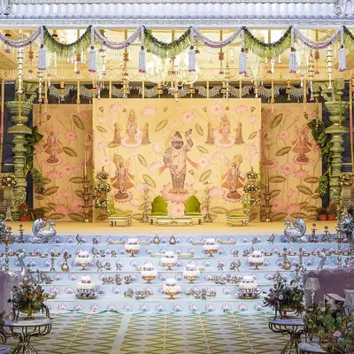The 'Eternal Krishna' comes to life in this opulent mandap design. The backdrop features intricate Pichwai-style paintings, while the stage is lined with rows of traditional brass lamps, creating a regal and divine atmosphere for the wedding ceremony.
