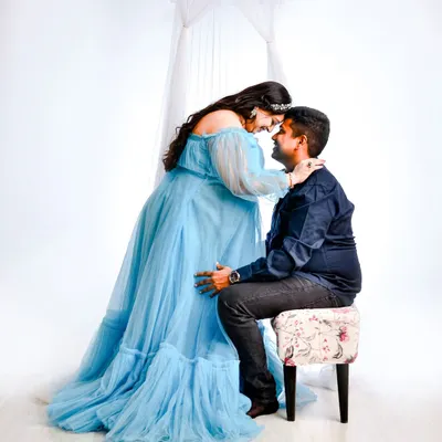 An intimate gaze between partners, framed by the soft fabric of our light blue maternity gown. These high-key shots create a bright, dreamy atmosphere.