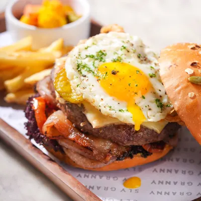 Take a bite of pure bliss. This is my signature burger, stacked high with a juicy patty, crispy bacon, cheese, and a perfectly fried egg.