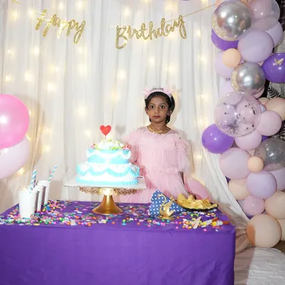 Seeing the birthday girl enjoy her special setup is the best part. This simple backdrop with fairy lights and a pastel balloon arch created the perfect spot for her to pose with her cake.