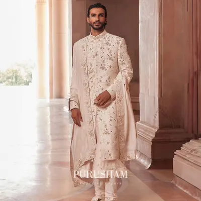 From my 'Takht' collection, this ivory sherwani is a study in grandeur. The surface is adorned with delicate, shimmering handwork, paired with a matching stole for a look of pure, understated royalty.