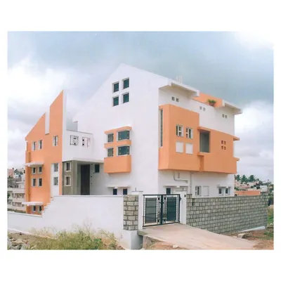 The exterior of 'Nachiar Illam', a 2,240 sq. ft. residence in Bangalore. The design makes strategic use of a corner plot, with distinct modular elements and a color palette that highlights its geometric form.