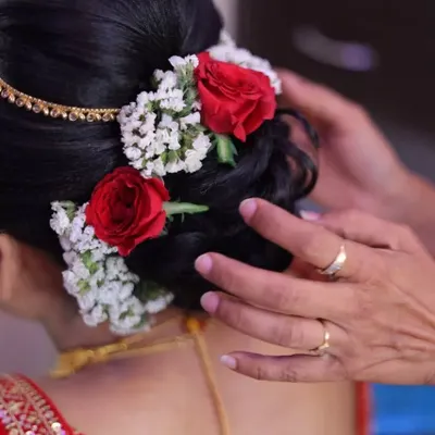 A close-up of a classic bridal bun. I've adorned this intricate updo with fresh red roses and baby's breath, adding a touch of romance and color.