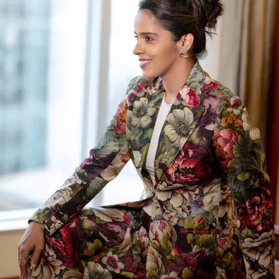 A candid portrait of Saina Nehwal, captured during a moment of relaxation. The natural light from the window gives the shot a soft, authentic feel, showcasing her personality beyond the badminton court.