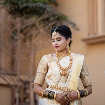 This bride looks serene and elegant for her muhurtham. Her makeup is classic and understated, with a focus on flawless skin and traditional gold jewellery that highlights her beautiful cream and gold silk saree.