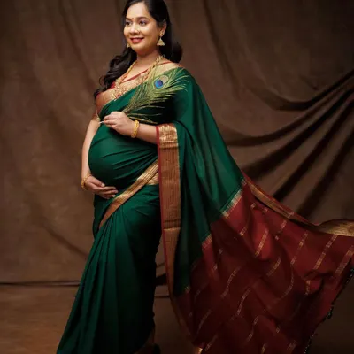 Draped in a magnificent green and red silk saree, this mother-to-be is the picture of grace and tradition. The peacock feather is a beautiful touch, symbolizing royalty and beauty.