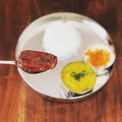 A single spoonful of my Bharwan Mirchi, or stuffed red chili pickle, served over a traditional Indian thali. The rich red color comes from the chilies and spices, with no artificial colors added.