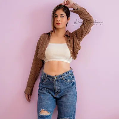 A simple, confident studio look. The clean background and modern styling with a crop top and jeans are perfect for building a model portfolio or for a bold personal branding shoot.