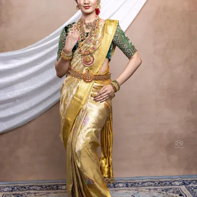 A complete South Indian bridal look. We designed the heavily embroidered green velvet blouse to pair with this stunning golden tissue Kanjeevaram saree for a grand and traditional Muhurtham ceremony.