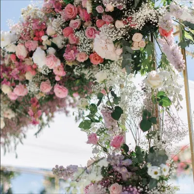 A close-up of the lush floral arrangement from a pastel-themed wedding stage. This detailed shot shows the beautiful combination of pink roses, white baby's breath, and fresh eucalyptus, highlighting our skill in floral artistry.