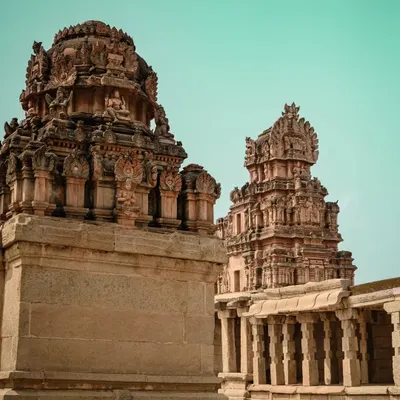 The majestic towers of the Virupaksha Temple in Hampi against a teal sky. My editing style brings a cinematic quality to architectural shots, highlighting their grandeur.