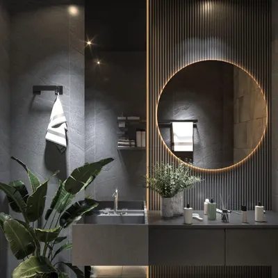 A luxurious dark-themed bathroom design. This space uses slate-grey tiles, a backlit circular mirror, and ribbed wall paneling to create a moody and sophisticated atmosphere, enhanced by indoor plants.