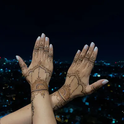 A clear view of the jewellery-inspired design on the back of Divya Spandana's hands. The patterns are designed to elongate the fingers and adorn the hands beautifully.