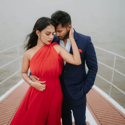 A bold and stylish portrait on a yacht in Goa. The vibrant red dress against the blue water and sky creates a striking, high-fashion look for a destination pre-wedding shoot.