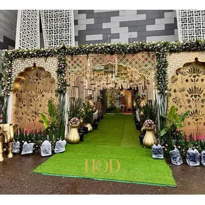 A truly grand entrance for a royal wedding, featuring intricate golden jali work, lush greenery, and auspicious elephant statues to welcome guests with traditional elegance.