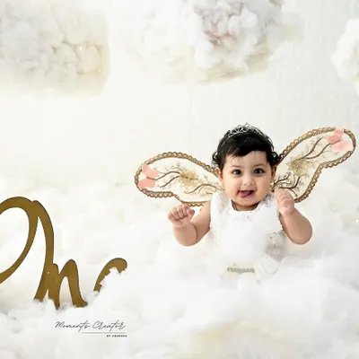 A little angel floating on a cloud. With delicate, shimmery wings and a happy smile, this baby girl looks absolutely heavenly in this all-white, dreamy setup.