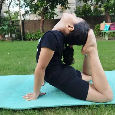 Here, a young student performs a deep backbend on the mat, improving her spinal mobility and control. This foundation is key for advanced martial arts movements.